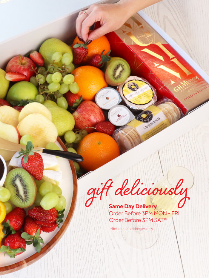 Assorted fruits and a box of chocolates on a white surface with 'Gift Delicious' text.
