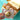Packaged donuts with colorful sprinkles and a 'Happy Birthday' card against a turquoise background